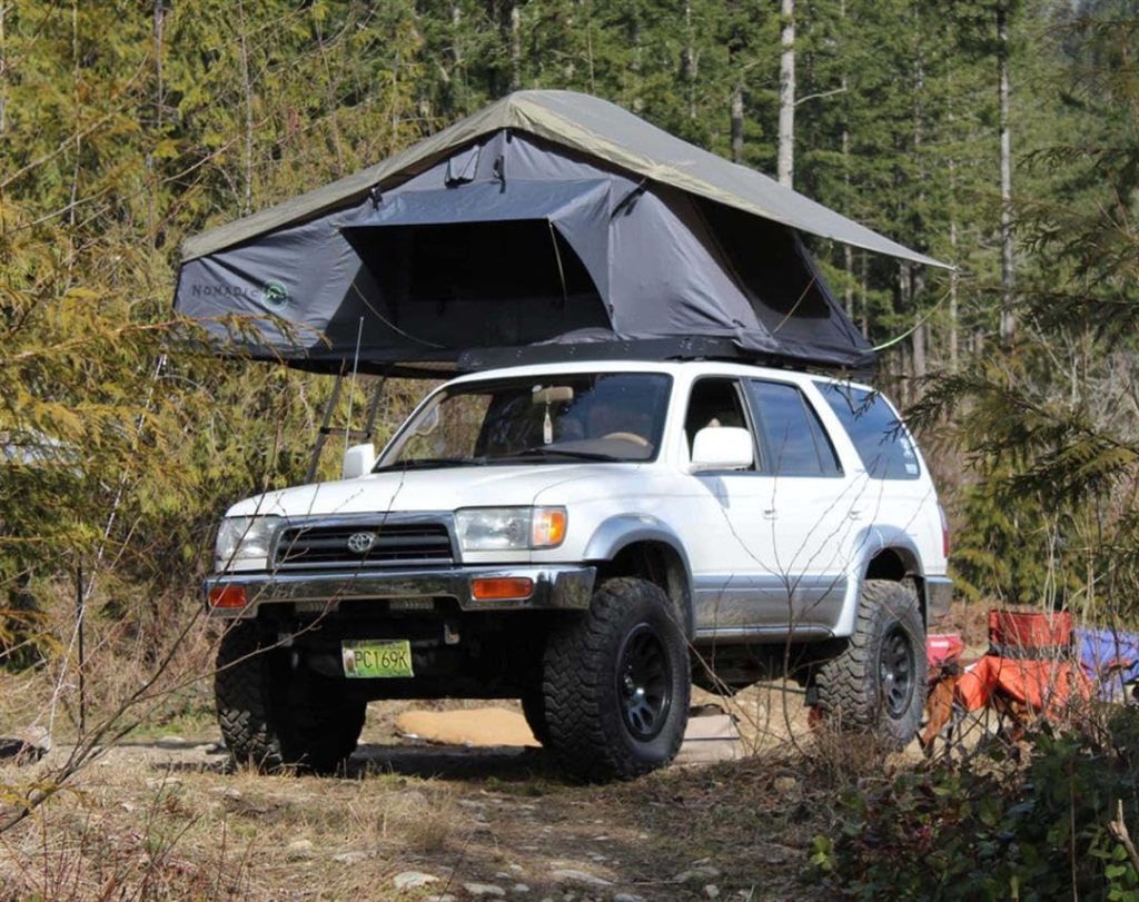 Overland Vehicle Systems Nomadic 3 roof top tent mounted on a 4x4 in the woods