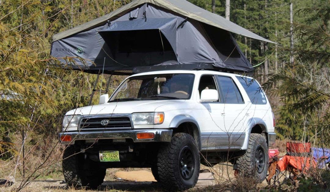 Overland Vehicle Systems Nomadic 3 roof top tent mounted on a 4x4 in the woods